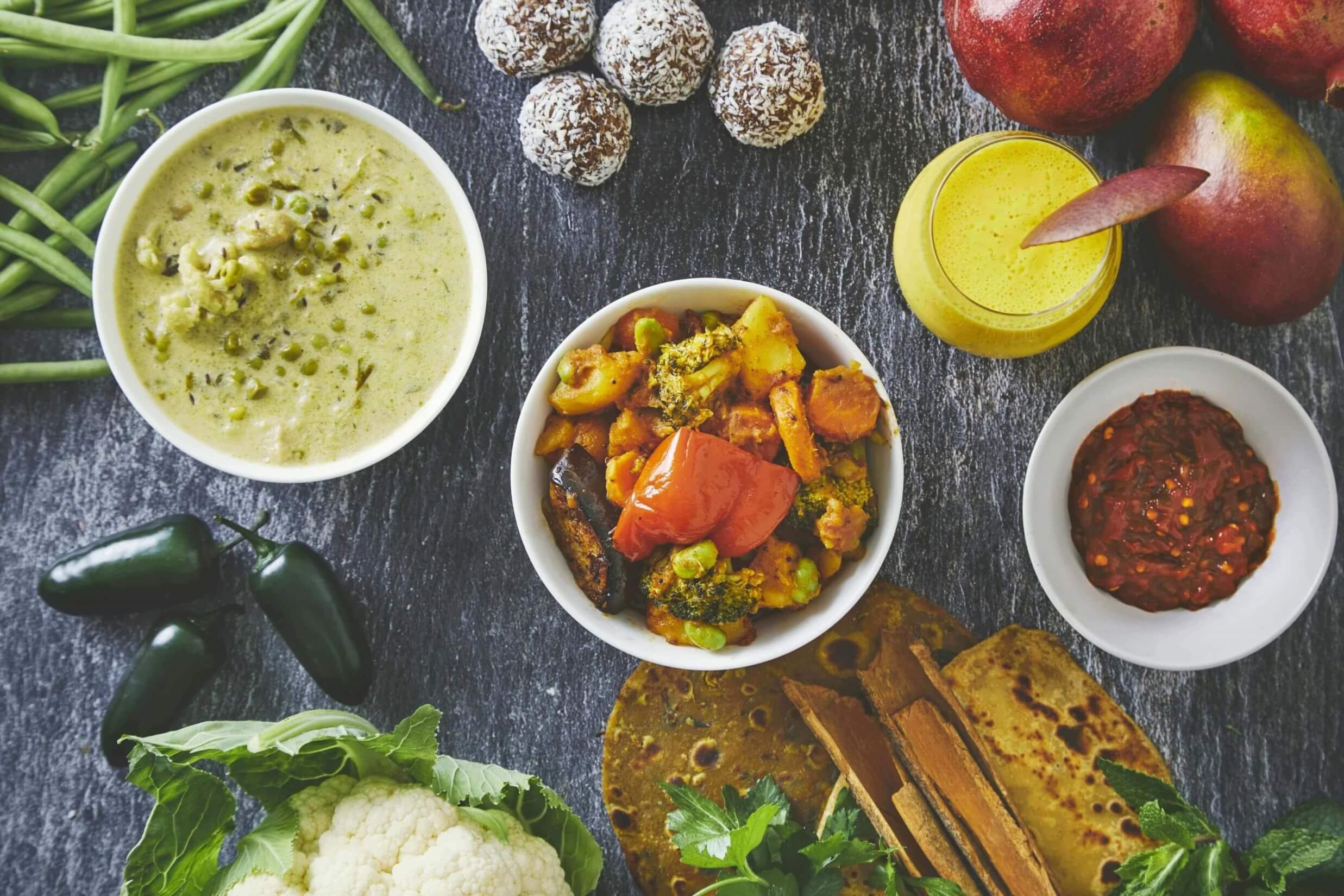 A spread of curries, flatbread, mango lassi and laddoo