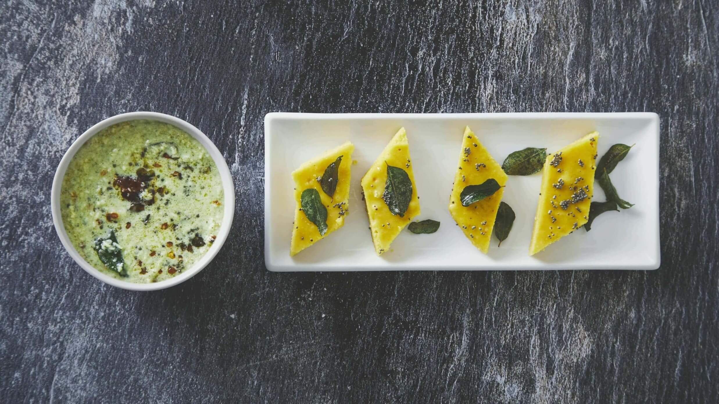 Khaman dhokla topped with curry leaves