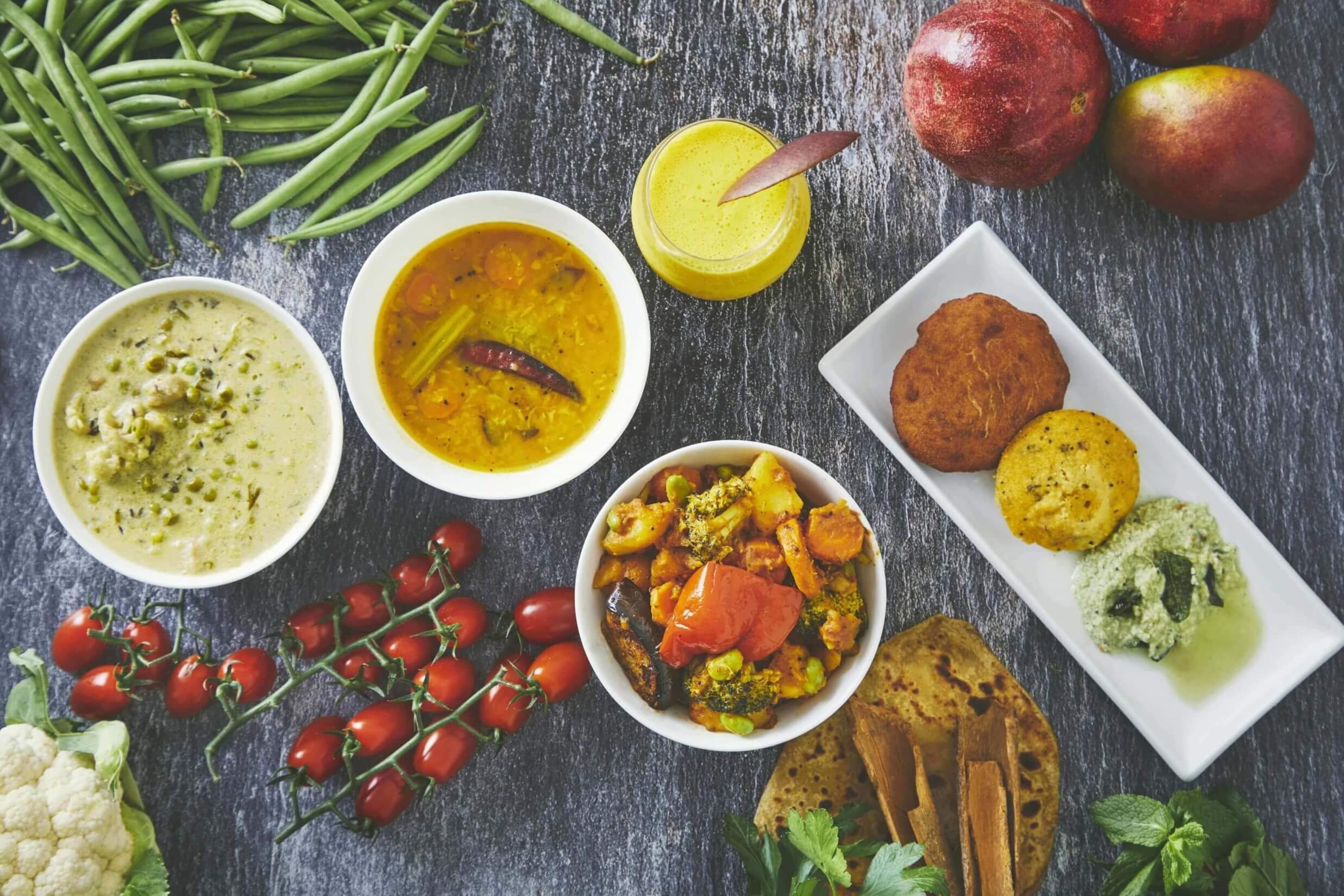 A spread of curries, flatbread and fresh produce